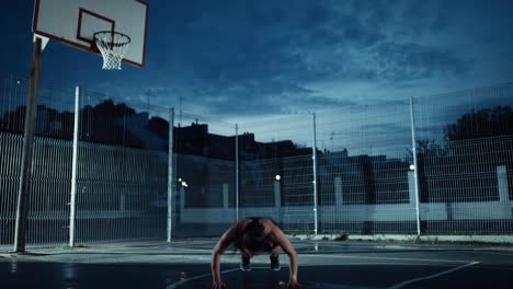 Adecuación-energética-hermosa-chica-haciendo-ejercicios-Jack-Burpee.-Ella-está-haciendo-un-entrenamiento-en-una-cancha-de-baloncesto-al-aire-libre-cercado.-Imágenes-de-noche-después-de-la-lluvia-en-una-zona-de-barrio-residencial.