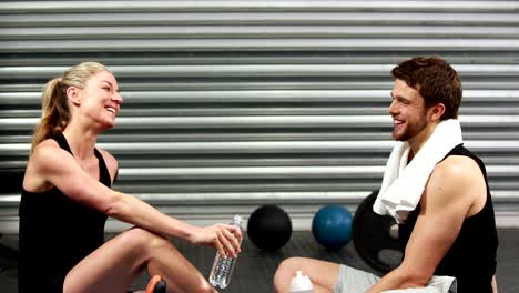 Smiling-fit-couple-sitting-on-mat-talking