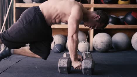 Una-forma-de-hombre-joven-haciendo-flexiones-con-pesas-en-el-gimnasio