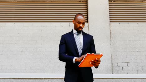 African-American-businessman-stand-with-tablet-outdoors