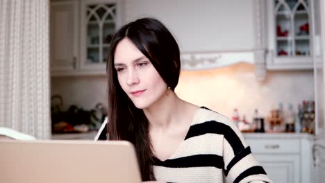 Porträt-einer-schönen-junge-Brünette-Frau-nutzt-Laptop-in-ein-helles-Esszimmer