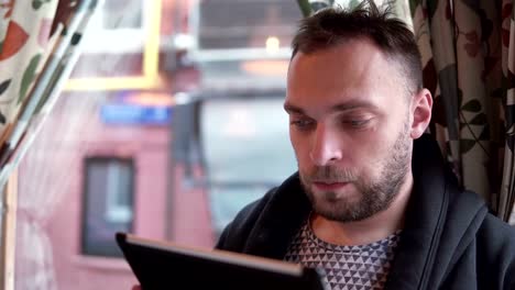 handsome-bearded-man-using-tablet-computer-touchscreen-in-cafe