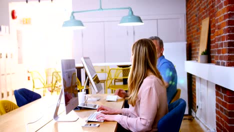 Business-executives-talking-while-working-on-computer