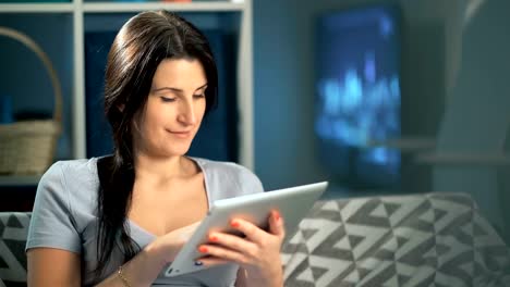 Woman-using-digital-tablet-at-home-sitting-on-sofa