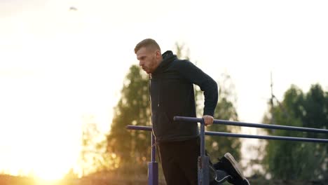 Hübscher-muskulöser-junger-Mann-haben-Training-Training-im-Park-auf-Sonnenuntergang