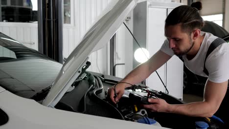 Service-station,-Professional-mechanician-male-stands-near-open-hood-checks-wiring-automobile-system,-Engine-review,-technical-condition
