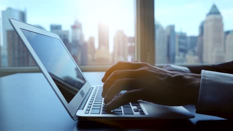 Business-Man-Using-Computer-with-Charts,-Diagrams,-Graphs-and-Figures.-Typing-on-Keyboard-of-Laptop.-Cityscape-in-the-Background.