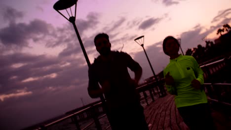 Young-couple-running-together-outdoors-after-sunset