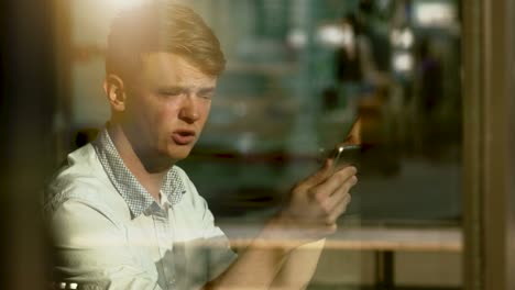 Blonder-Jüngling-mit-einer-Videokonferenz-über-Digital-Tablette.-Lächeln-auf-den-Lippen-und-an-seinen-Freund-und-Kollegen-kommunizieren.