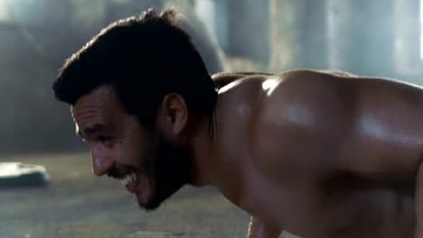 Close-up-Shot-of-a-Muscular-Shirtless-Man-Athlete-Doing-Push-ups-as-Part-of-His-Fitness-Exercise-Program.-He's-Covered-with-Sweat-and-Works-out-in-Deserted-Factory-Remodeled-into-Gym.