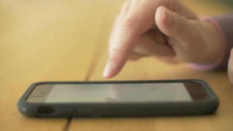 Closeup-Shot-Of-Woman-Scrolling-Screen-On-Smartphone-At-Table