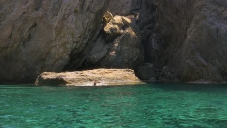 Young-woman-swimming-in-the-sea-near-a-cliff