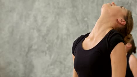 El-grupo-de-mujeres-jóvenes-tiene-clase-de-yoga,-haciendo-poses-de-Guerrero-en-el-gimnasio