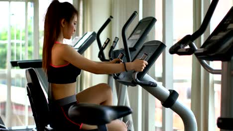 Sport-Frau-erarbeiten-mit-spinning-Bike-im-Fitness-Studio