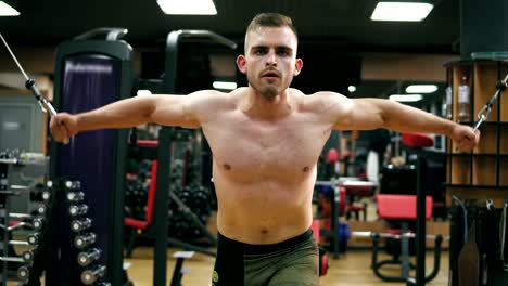 Vista-de-cerca-de-un-hombre-atlético-guapo-sin-camisa-haciendo-pectorales-en-el-trainer-de-crossover-en-el-gimnasio.-Rodada-en-4k