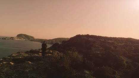 Man-in-elegant-suit-with-briefcase-running-on-top-of-a-cliff-on-an-island-and-exulting