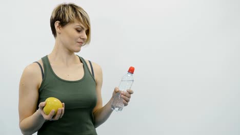 Mujer-con-manzana-y-agua-en-el-gimnasio