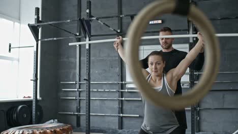 Entrenador-personal-ayudando-a-mujer-haciendo-sentadillas-con-barra