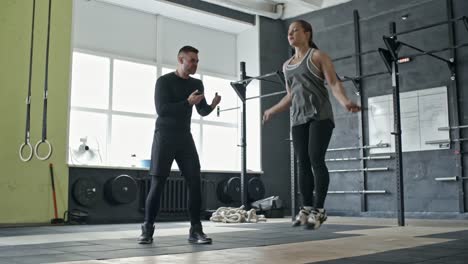 Entrenador-personal-motivación-mujer-durante-ejercicio-de-saltar-la-cuerda
