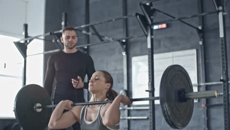 Personal-Trainer-Controlling-Woman-Exercising-with-Barbell