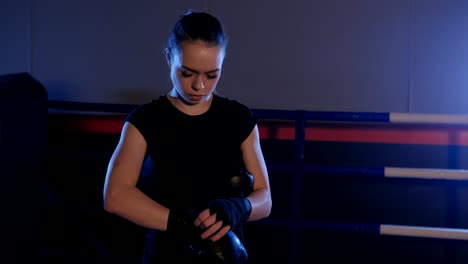 Beautiful-kickboxing-woman-dresses-boxing-gloves-in-the-boxing-hall.