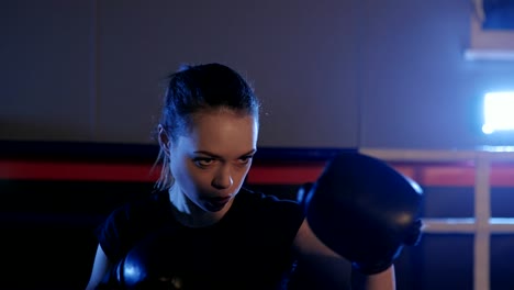 Boxer-de-kickboxing-hermosa-mujer-lanzando-golpes-en-la-sala-de-boxeo.