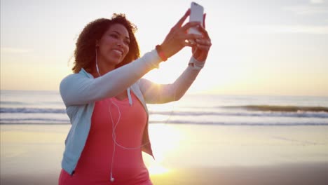 Étnica-mujer-teniendo-playa-selfie-en-llamarada-de-sol