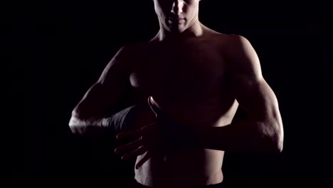 Male-boxer-wraps-his-hands-with-handwrap.-professional-boxer-wrapping-bandages-on-his-hand.-Fighter-wrapping-hands-with-boxing-wraps-in-the-gym