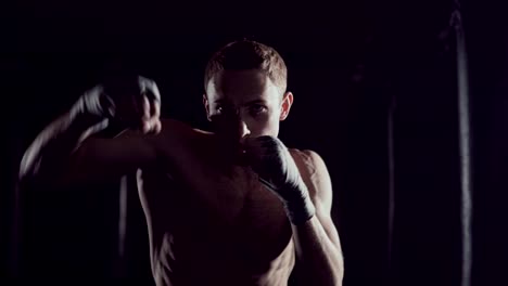 Kickboxer-Schattenboxen-als-Übung-für-den-Kampf.-Kämpfer,-die-Ausbildung,-Stanzen.-Boxen-in-der-Dunkelfärbung.-Junge-Boxer-training-in-der-Turnhalle