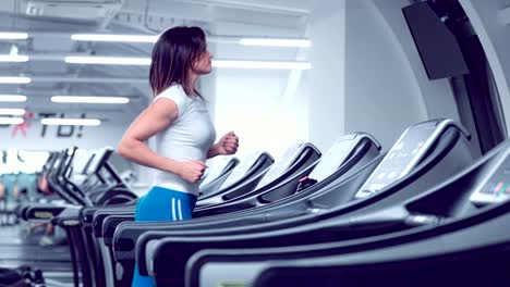 Adult-woman-runs-on-treadmill-at-the-fitness-centre.-Attractive-sporty-girl-running-on-the-treadmil