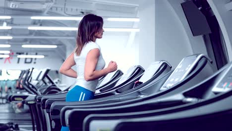 Adult-woman-runs-on-treadmill-at-the-fitness-centre.-Attractive-sporty-girl-running-on-the-treadmil