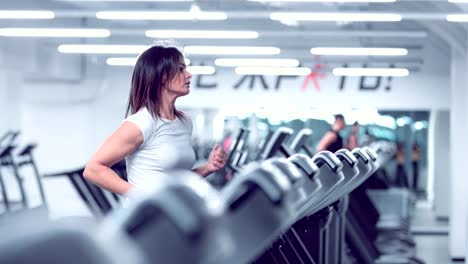 Adult-woman-runs-on-treadmill-at-the-fitness-centre.-Attractive-sporty-girl-running-on-the-treadmil