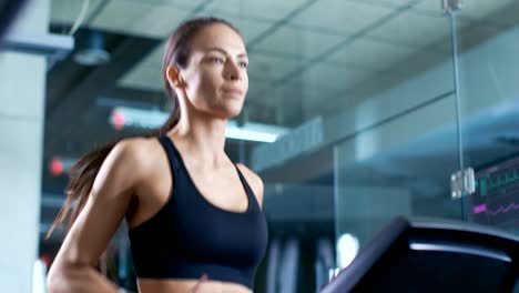 Hermosa-mujer-atleta-llevar-sujetador-de-deporte,-camina-en-una-cinta-de-correr,-ejercicio-de-entrenamiento.-En-el-fondo-moderno-gimnasio-/-Fitness-Club.