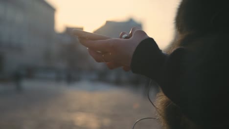 Woman-hands-using-touchscreen-phone-outdoors-in-city