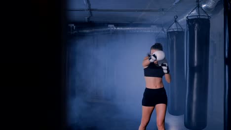 Young-woman-shadow-boxing-in-a-smoky-gym