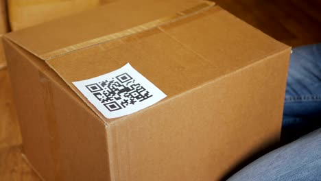 A-man-pastes-a--QR-code-on-a-box.-Delivery-service.-Online-shop.-Bar-code.