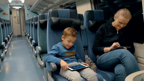 Family-traveling-by-train-and-entertaining-with-electronics