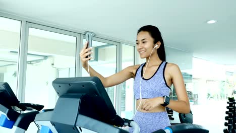 Woman-using-smartphone-while-exercise.-Asian-woman-Exercise-at-gym.-Sport-and-Reaction-concept.-4k-Resolution.