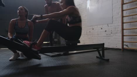 Mujer-haciendo-ejercicio-en-máquina-de-la-fila-con-entrenadores