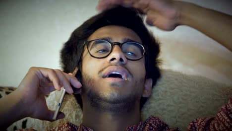 Close-up,-Handsome-Indian-Man-In-Glasses-Talking-On-Phone-Sitting-On-Sofa