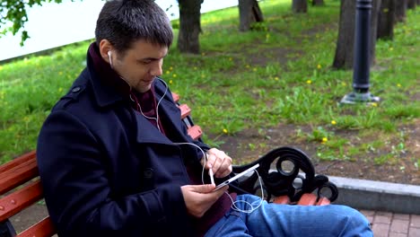 Ein-Mann-hört-Musik-und-arbeitet-auf-einem-Tablet-im-Park.