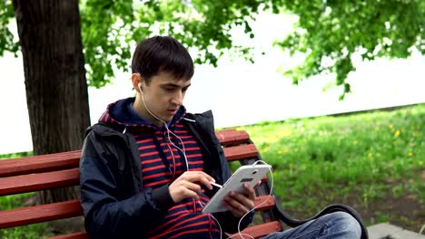 El-hombre-está-utilizando-una-tableta-en-el-parque.