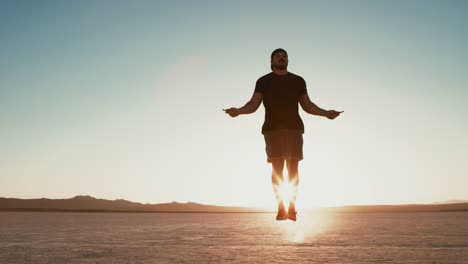 Slow-Motion-sportlicher-Mann-arbeiten,-draußen-in-der-Wüste-bei-Sonnenuntergang-Seilspringen