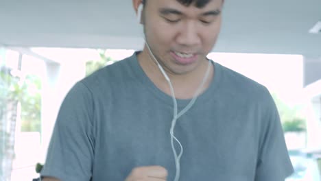 Young-asian-man-running-on-the-treadmill-in-the-gym-with-earphones