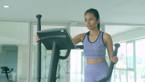 Asian-girl-exercising-cardio-on-the-elliptical-machine-in-the-gym