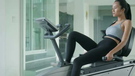 Asian-sport-women-riding-a-stationary-bike-in-the-gym