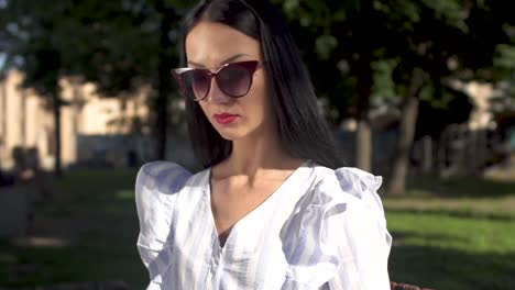 Schöne-junge-Frau-in-Sonnenbrille-Eingabe-auf-ihrem-Laptop-im-park