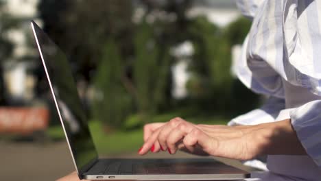 Mujer-de-negocios-trabajando-en-ordenador-portátil-sentado-en-un-banco-de-Parque