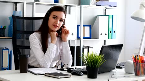 woman-propping-head-in-hands,-straightening-headset-and-looking-into-camera