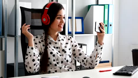 businesswoman-in-red-headphones-shooting-video-on-smartphone-in-modern-office